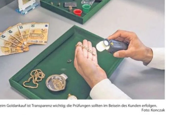Foto aus der Reportage der Delmenhorster Kreiszeitung: Goldprüfung am Tisch — Hand mit Lupe und Goldkette, Münzen und Euro-Scheine auf grünem Samttablett, Bildunterschrift „Beim Goldankauf ist Transparenz wichtig